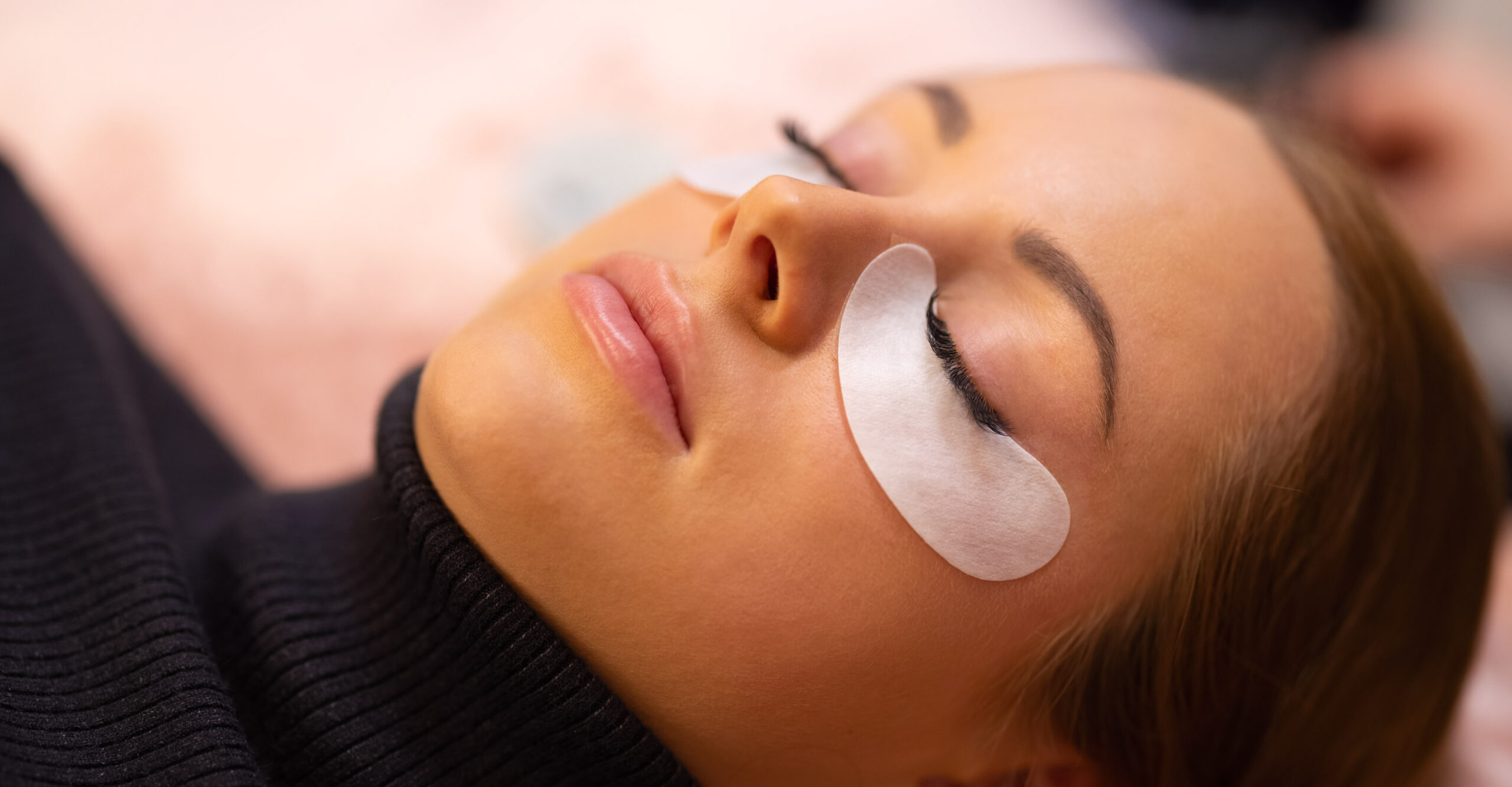 person laying down with cotton pads under their eyes
